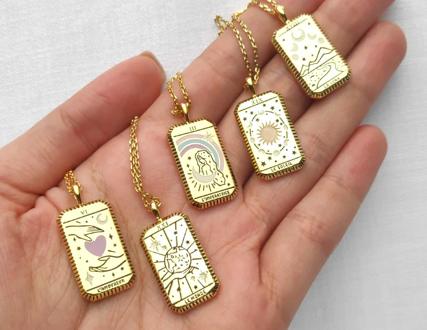Gold tarot card pendants on gold necklace.