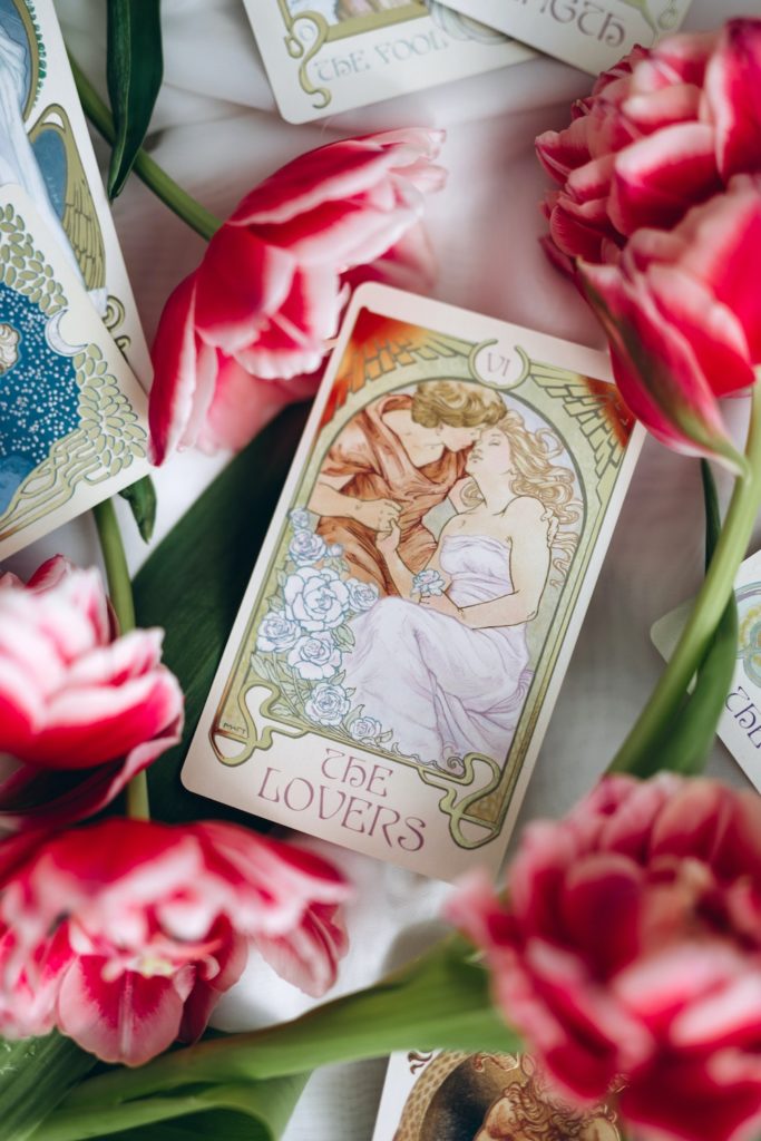 The Lovers Tarot Card amongst red flowers.
