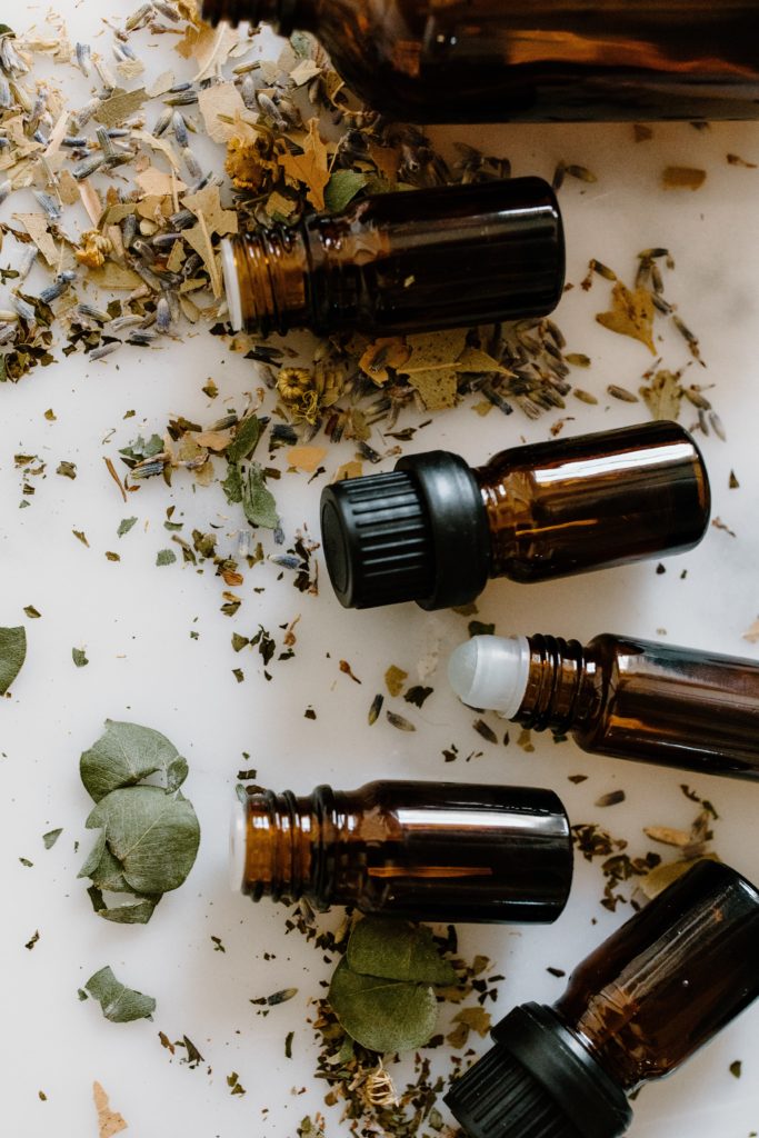 Essential Oil Bottles and Herbal Medicine on White Surface