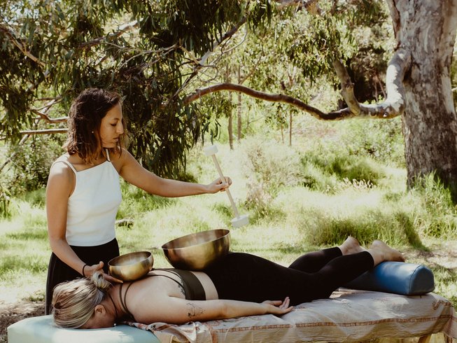 A woman practicing sound healing and meditation in the bushland during a yoga retreat in Australia.