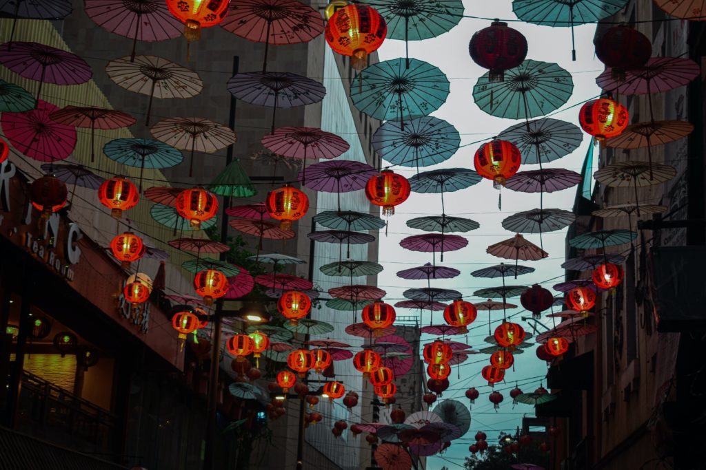 Colorful Umbrellas Hanging Beside Red Lanterns