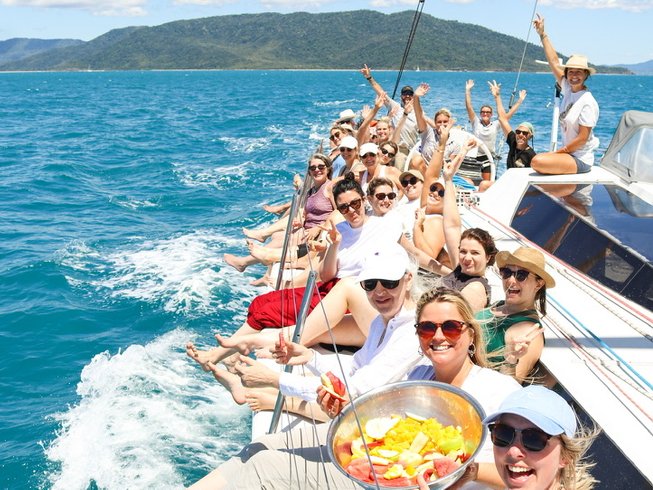 A sailing yoga retreat in Australia featuring a group of people smiling while on a yacht on the ocean.