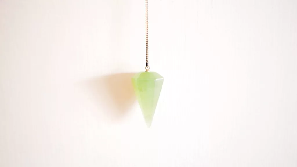 Green Jade crystal pendulum on a chain.